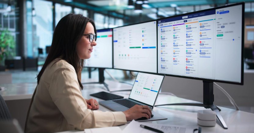 A recruiter reviewing candidates across several monitors in a modern office